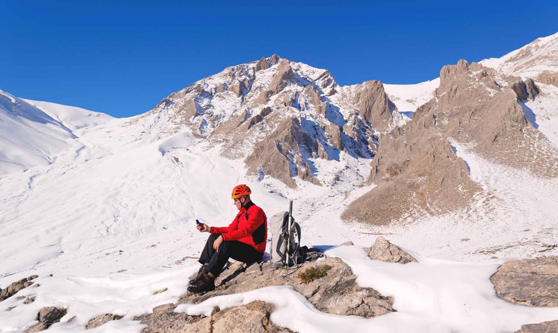 man sat on a snowy mountain placing an order using his phone